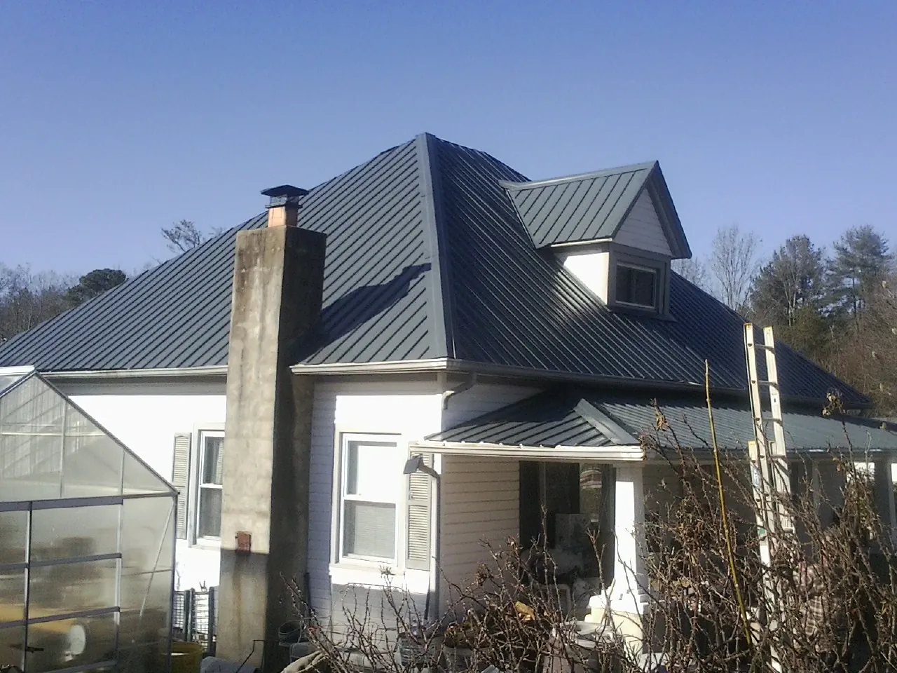 Dark blue standing seam metal roof on a white farmhouse with dormer — Slate & Tile Roof Repair by Roofing Brothers in East Windsor