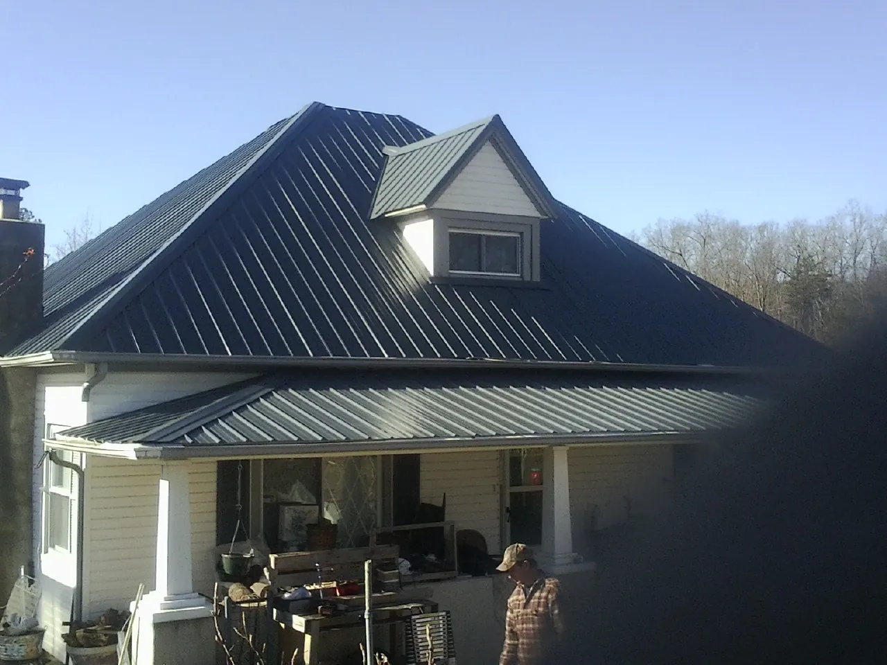 Dark blue standing seam metal roof with a dormer above a front porch in East Windsor