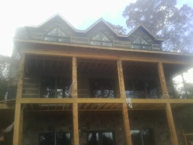 Dormers and porch framing on a large log home under construction — Roof Coating work by our crew in East Windsor