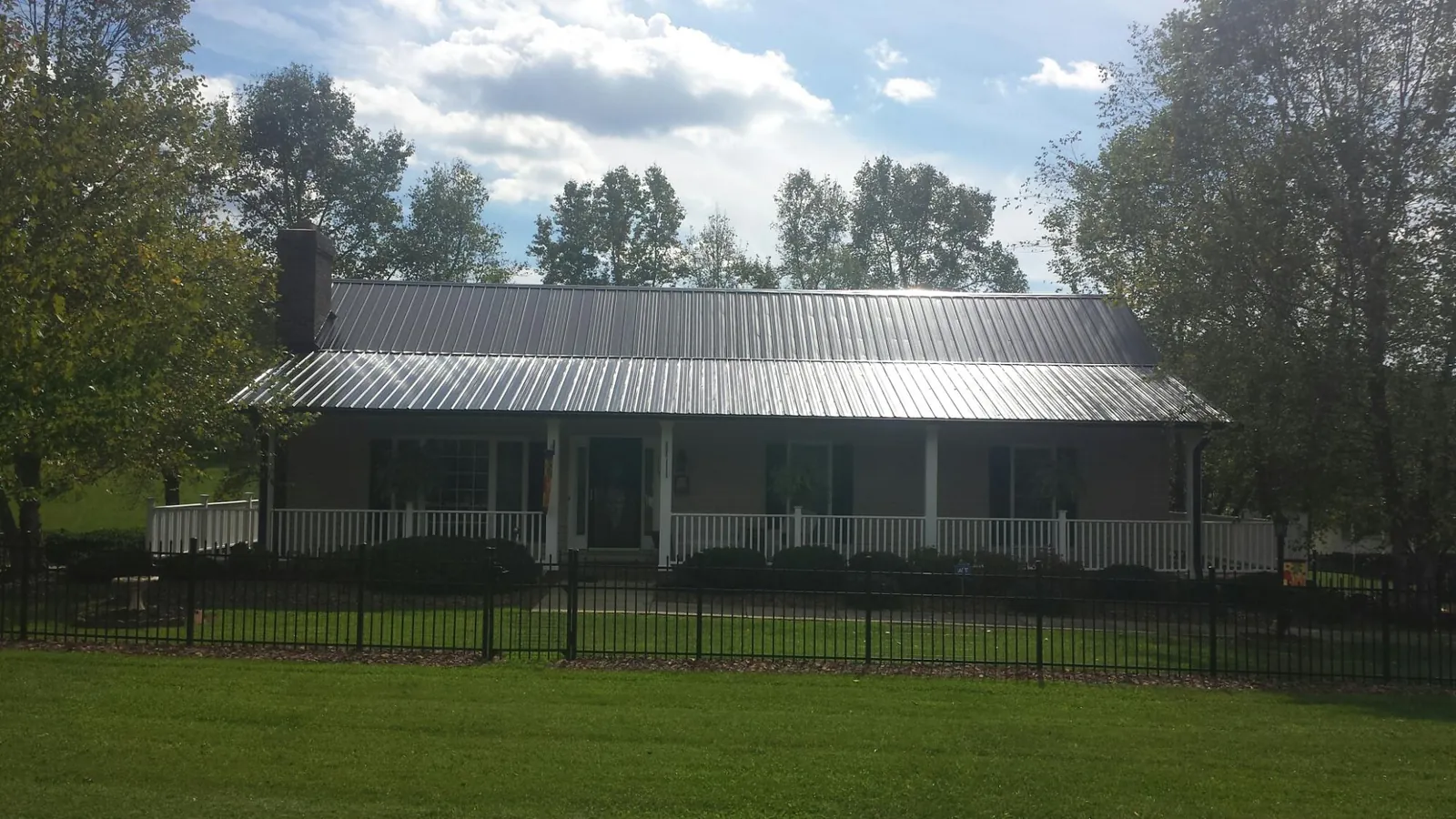 Gray metal roof on a brick ranch with a full width front porch — Gutter Guard Installation work by our crew in East Windsor