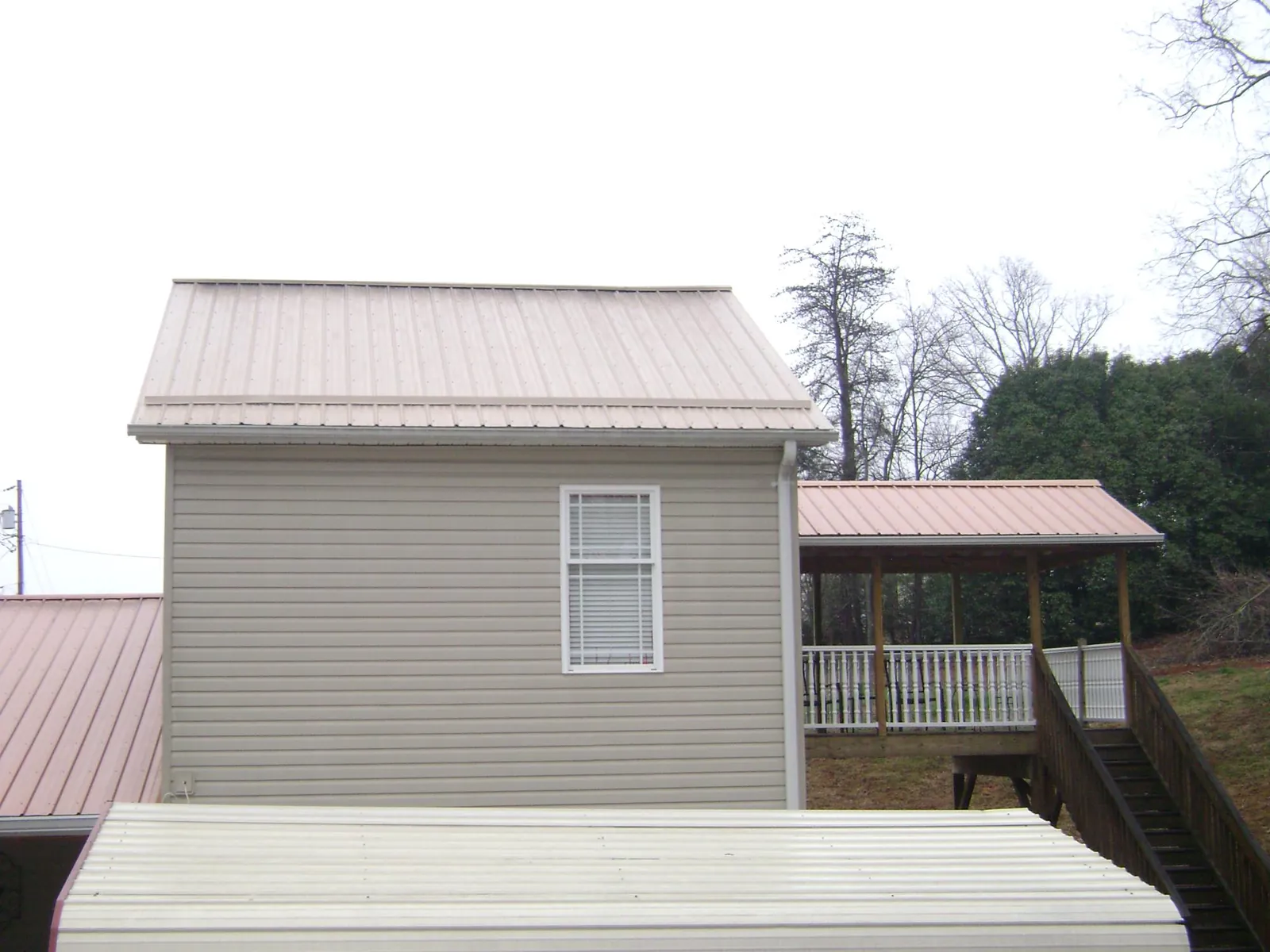 Tan metal roofs on a two story addition and attached porch, from a Roof Replacement job in East Windsor