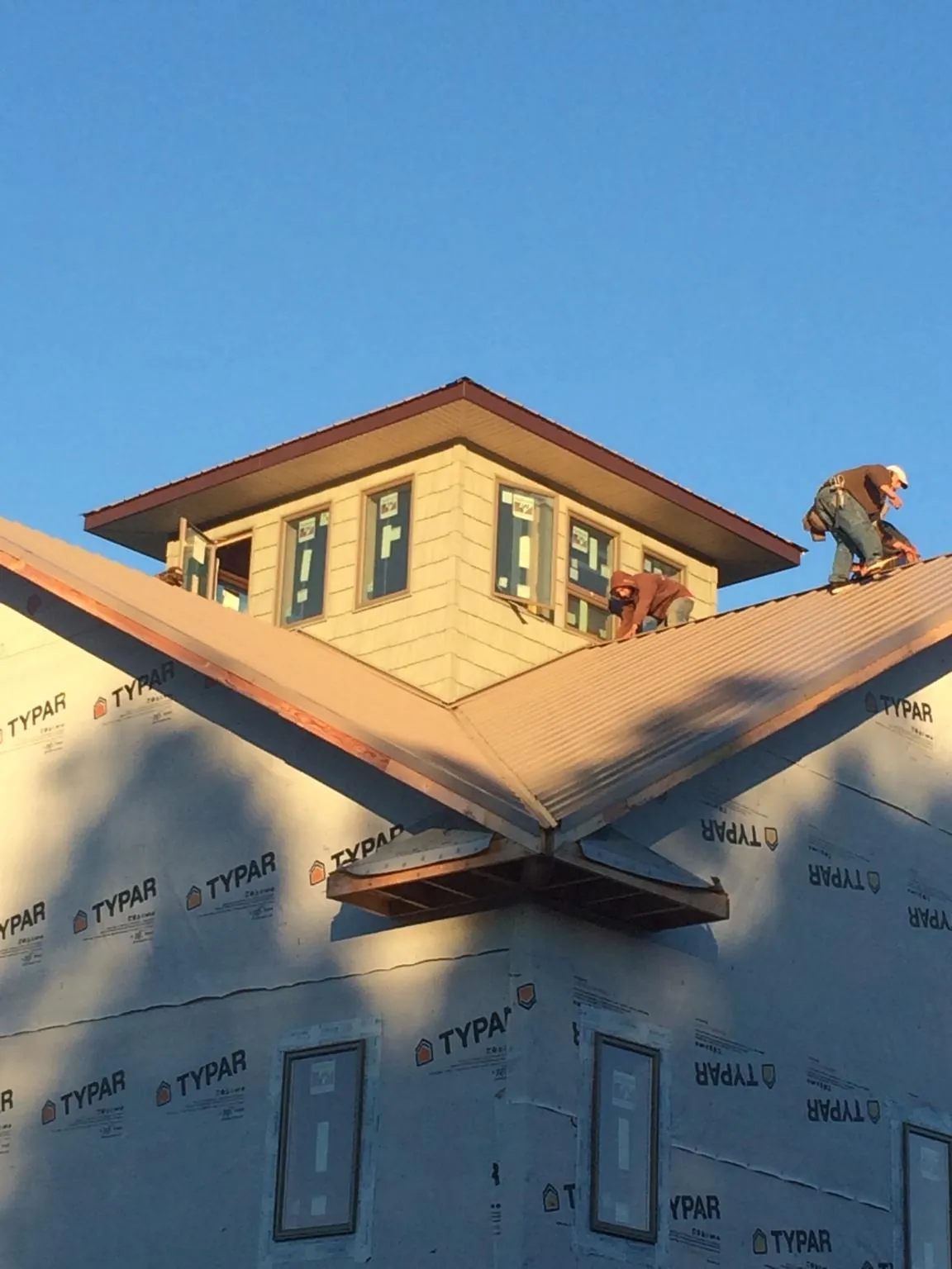 Roofers working around a rooftop cupola on a new metal roof at sunset — Roof Waterproofing in East Windsor by Roofing Brothers
